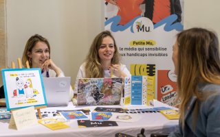 URRH 2023 - Photo du stand "La petite Mu". Echange entre un participant et les fondatrices de "Petite Mu", Alice Deves et Anaëlle Marzelière.