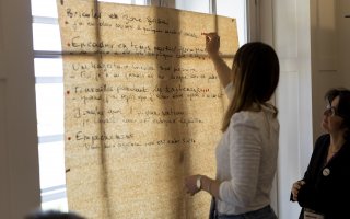 URRH 2023 - Photo d'une participante à l'un des ateliers de l'URRH. Sur une fenêtre, une page de paperboard est accrochée. Une personne colle une gommette rouge sur une phrase : Bricoler en zone grise, J'ai eu deux cancers à quelques années d'intervalle.