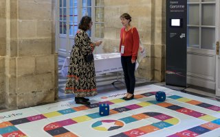 URRH 2023 - Photo de deux participants à l'événement jouant au jeu "Handipoursuite" sur un plateau géant.