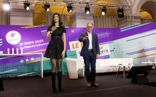 URRH 2023 - Photo de la cérémonie de remise du prix ADP, Apprentissage de la LSF. De gauche à droite : Sophie Vouzelaud, maitresse de cérémonie, qui apprend la Langue des signes française au public, et Hugues Defoy de l'Agefiph.