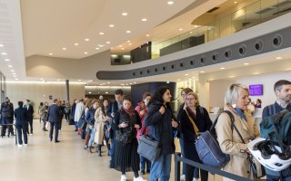 Prise de vue de l'accueil du public. Une foule attend de récupérer son badge pour entrer à l'événement. Dans le hall d'accueil du Carré des Docks.