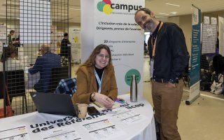 Photo du stand du Campus de l'inclusion. 2 personnes prennent la pose et sourient à la caméra.