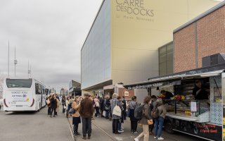 Photo de 2 foodtrucks présents à l'URRH : La Rôtisserie des 4 saisons et Conteneur à burger. Une petite foule attend d'être servi.