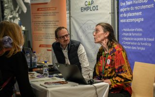 Deux exposants du stand France Travail et Chéops (Cap emploi), discutent avec des personnes