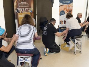 Photo de l'espace exposant. 3 personnes (prise de photo de dos) sont assises sur des chaises et sont massées par 3 masseurs. Exposant Be So Phorn