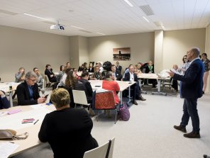 Photo d'un atelier pratique. Des personnes sont assises et écoutent un des animateurs qui a la parole.