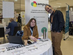 Photo du stand du Campus de l'inclusion. 2 personnes prennent la pose et sourient à la caméra.