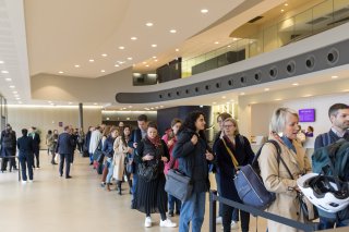 Prise de vue de l'accueil du public. Une foule attend de récupérer son badge pour entrer à l'événement. Dans le hall d'accueil du Carré des Docks.