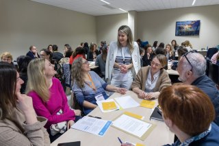 Photo d'un atelier pratique. Des participants sont assis et échangent avec une animatrice de la session.