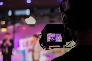 Au premier plan, une caméra et son caméraman capte le direct sur scène