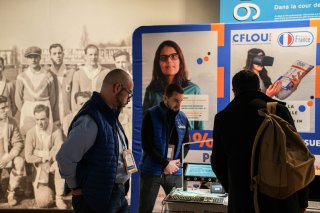 Photo du stand de l'exposant CFlou, avec des personnes qui s'arrêtent devant le stand