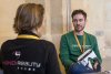 URRH 2023 - Photo de deux participants à l'événement. De dos et assise, une personne qui porte un t-shirt où il est écrit "Handireality". En face, un homme la regarde, il tient, à la main, un casque de réalité virtuelle augmentée.